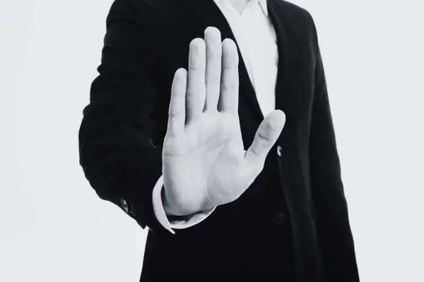 Mano extendida en señal de alto, con un traje oscuro. Representa el derecho de reversión, un límite claro.