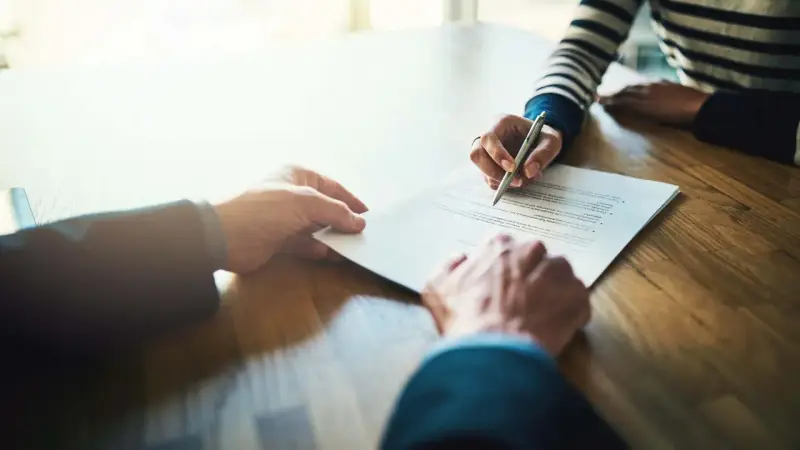 Manos firmando un contrato de alquiler de piso. Los padres avalan el alquiler.